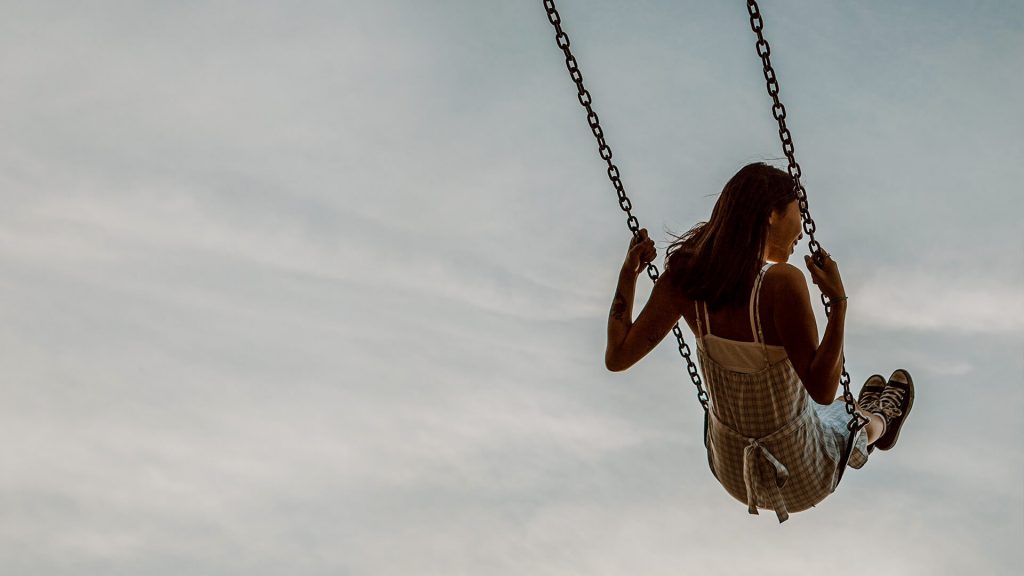 Woman on a swing against a cloudy sky, enjoying journey to inner peace
