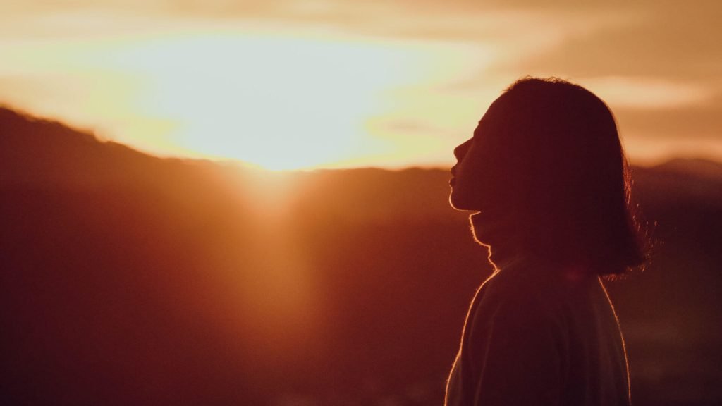 Woman basking in the glow of the setting sun, finding a way to build a happy life anyway