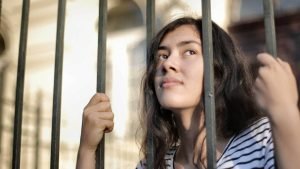 Teenage girl with her face between bars of a fence. What to say to persuade her to open up?